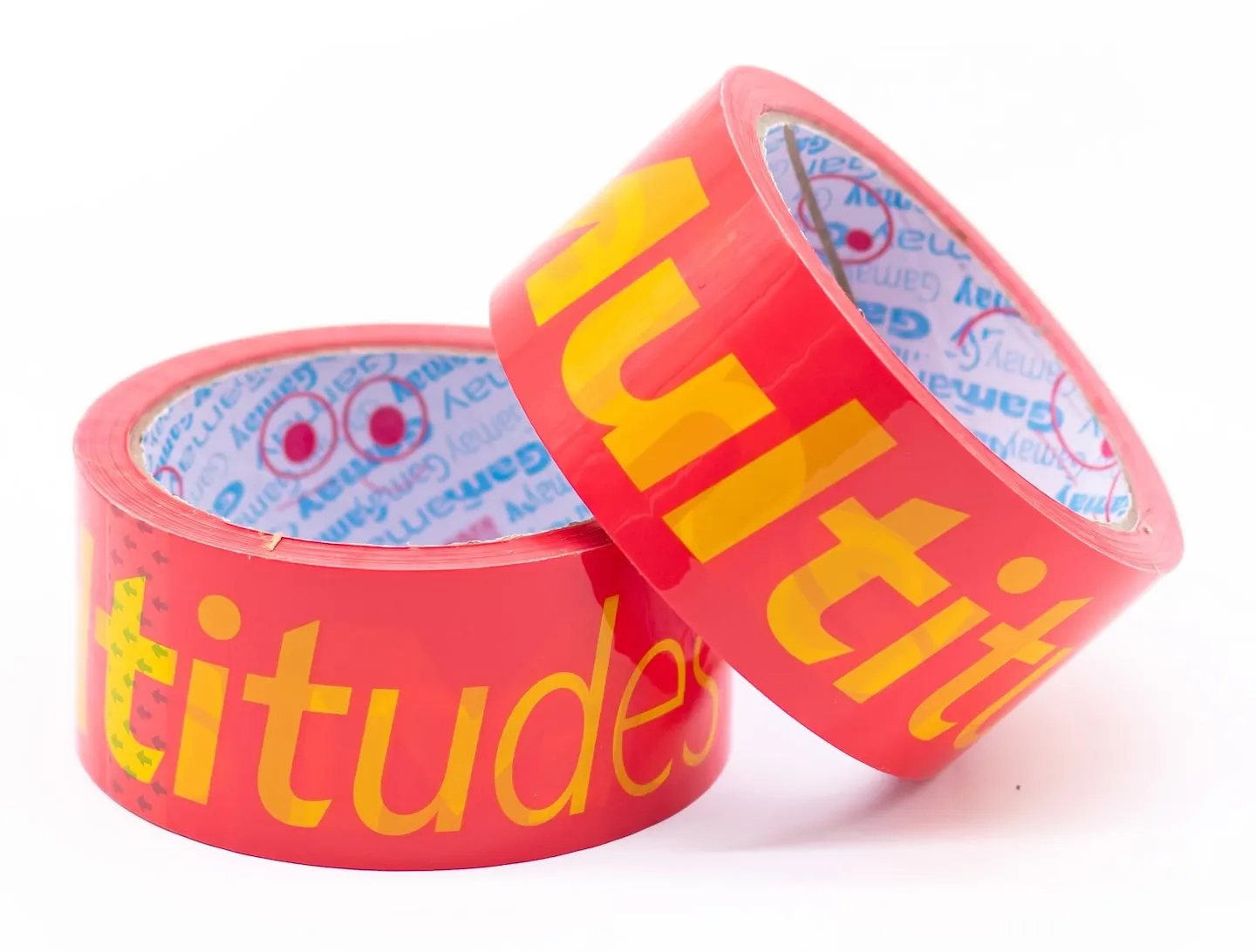 A roll of magenta packing tape with yellow letters across it reading “CONTAINS MULTITUDES”