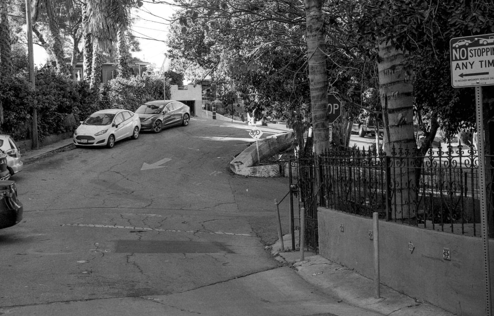 A steep one-way street leading up to an overgown median at an intersection