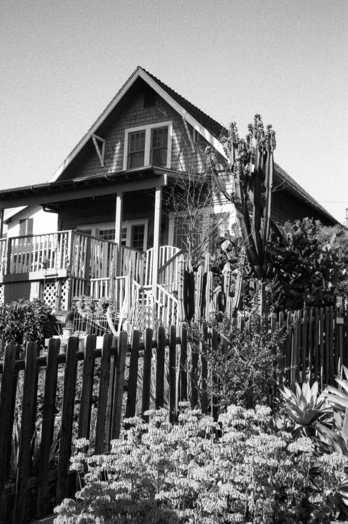 A house with a steep gable, pickett fence, and cacti growing in the garden