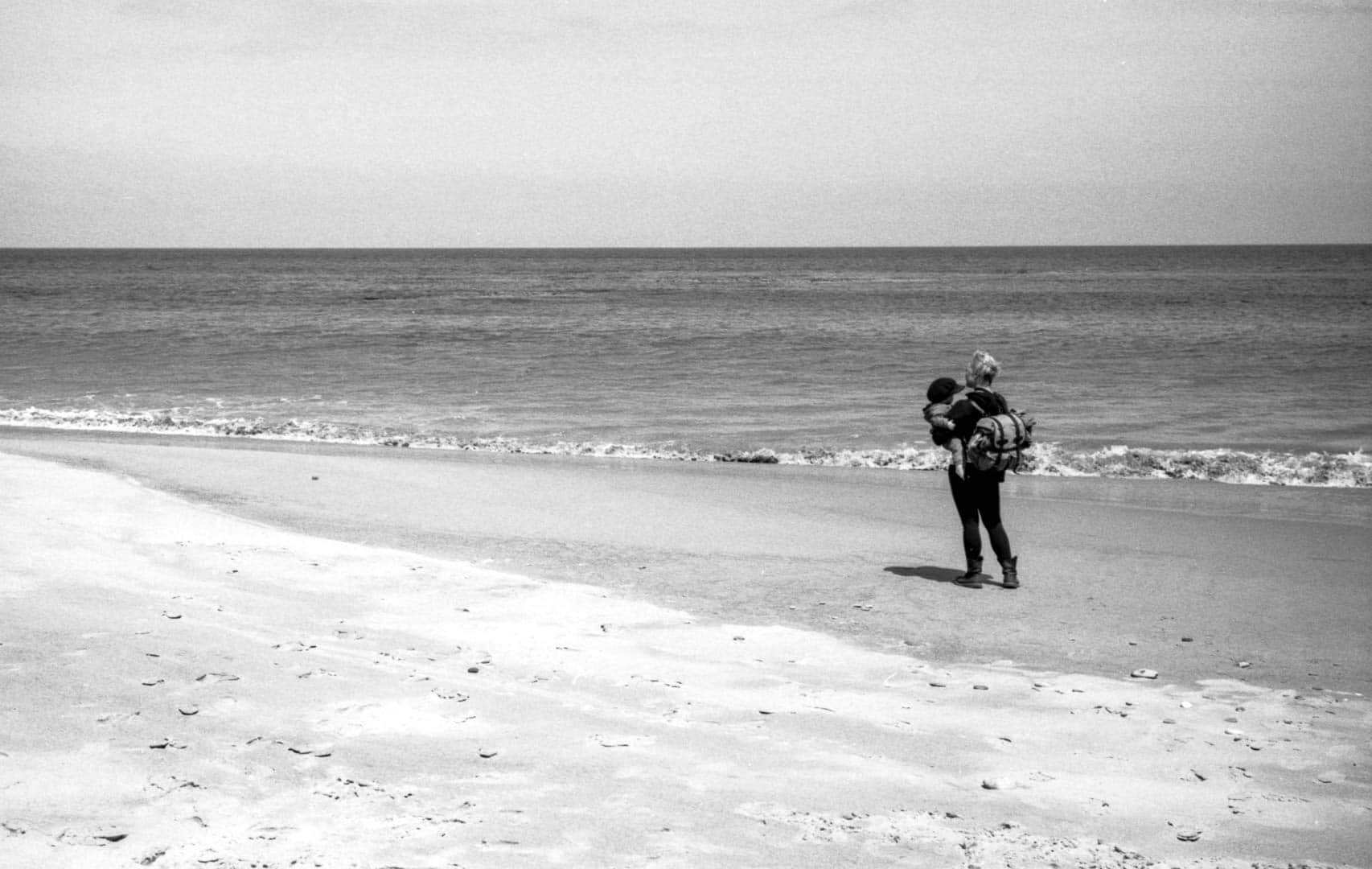 A woman and baby walking along the shore