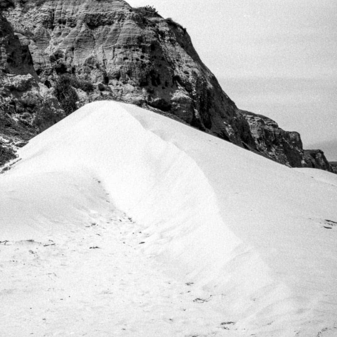 A large dune against a dark rocky bluff