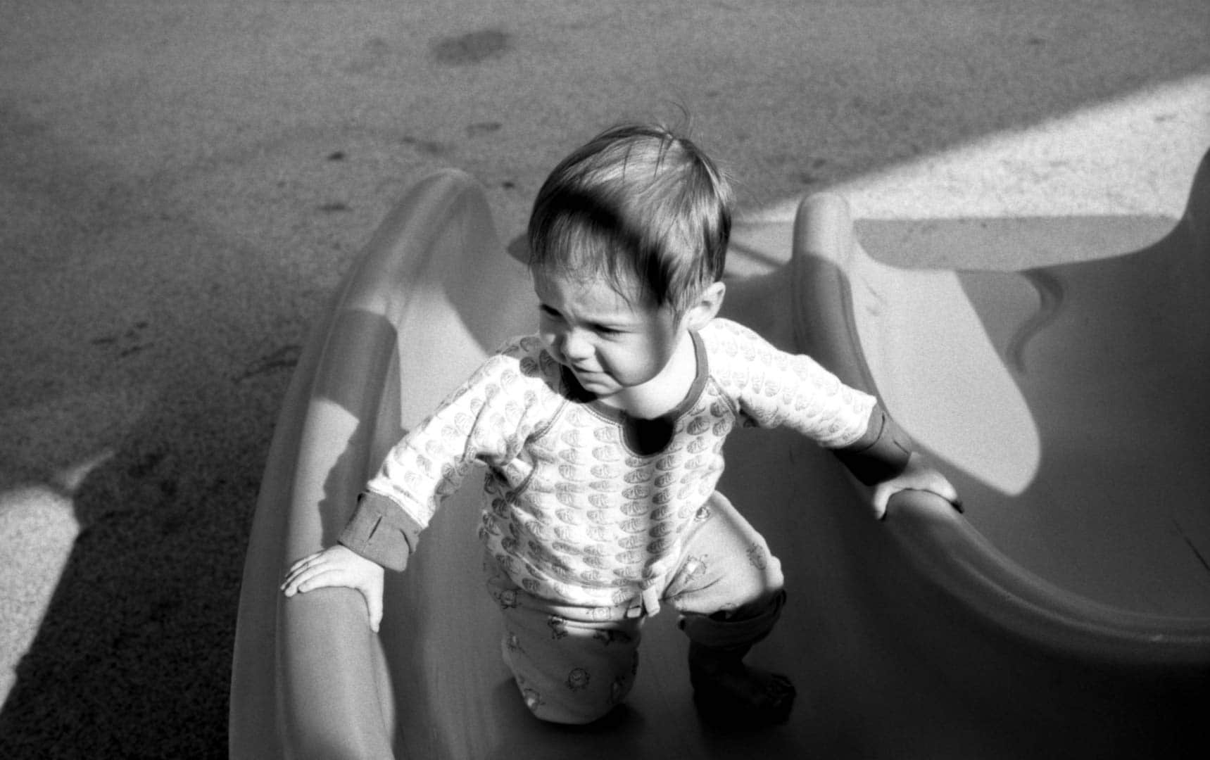 A baby trying to crawl up a slide on the playgound