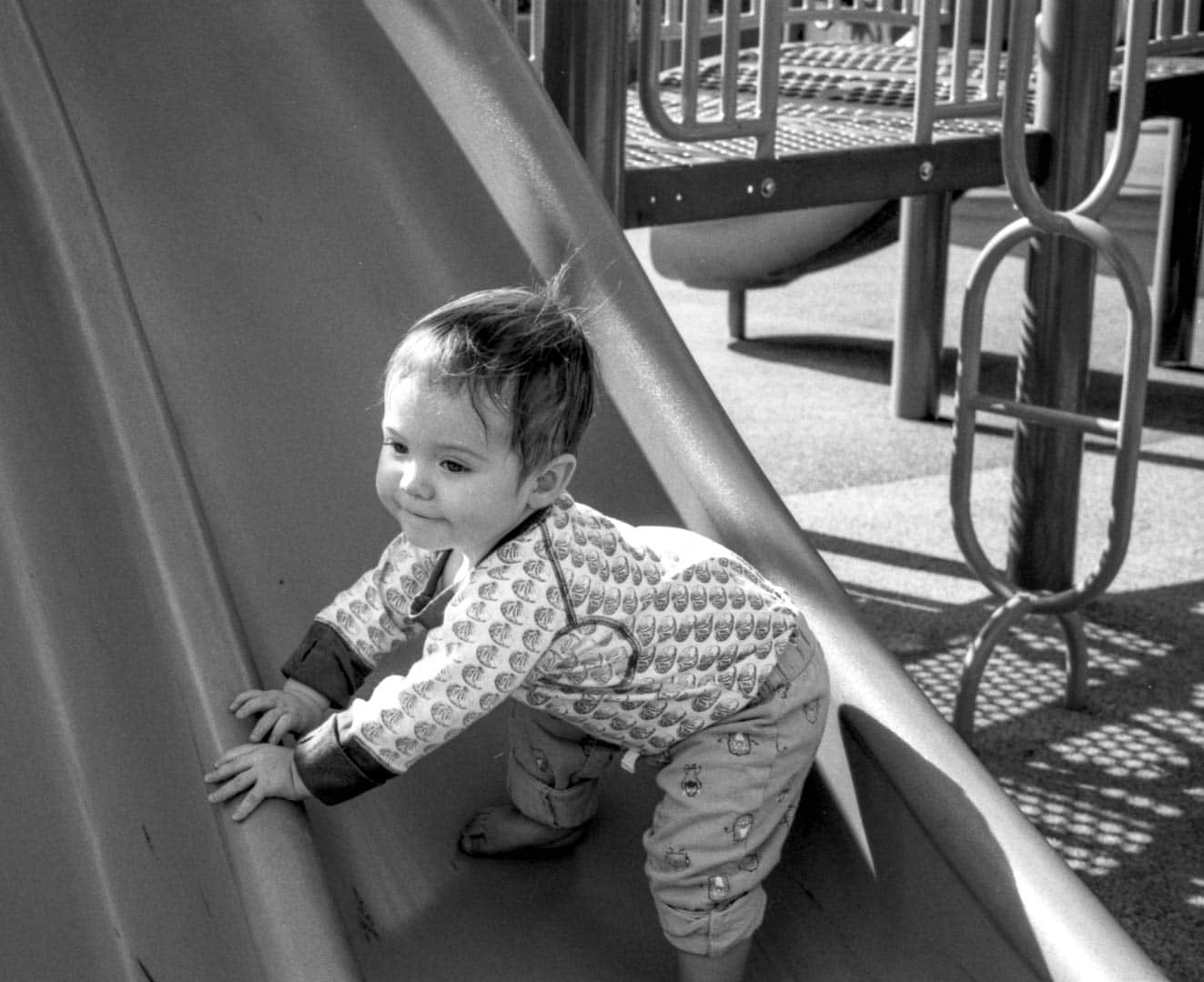 A baby trying to crawl up a slide on the playgound